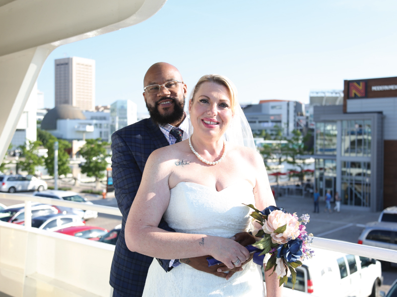 bride and groom, holding eachother, smiling while on the goodtime iii boat with the city in the background